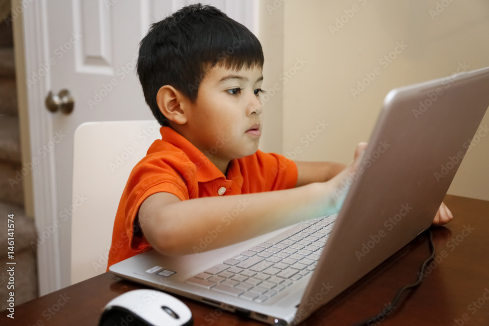 Native American boy sitting at table using laptop Native American boy sitting at table using laptop