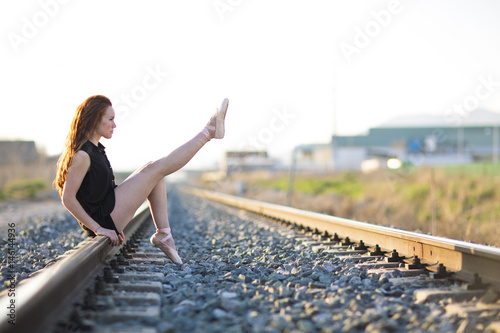 Ballerina posing on the railroad track. photo