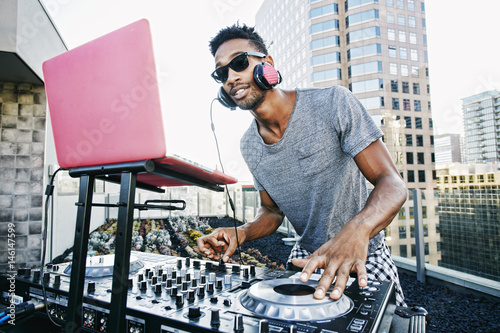 Smiling Black DJ on urban rooftop photo