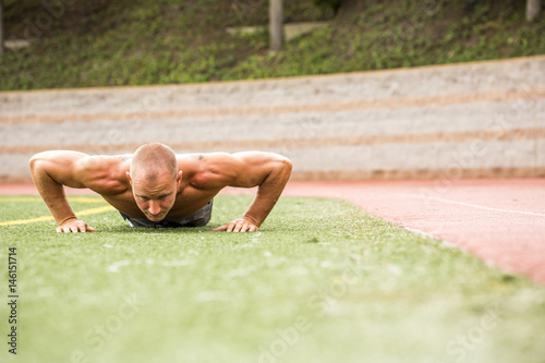 Caucasian man doing push-ups on sports field