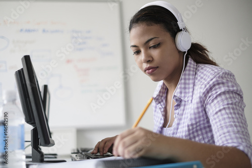 Hispanic woman in computer lab writing in notebook photo