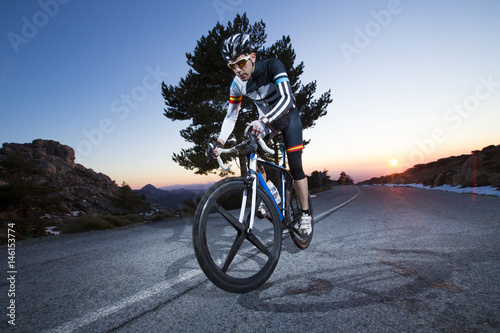 Fototapeta Naklejka Na Ścianę i Meble -  Cyclist man riding mountain bike at sunset on a mountain road