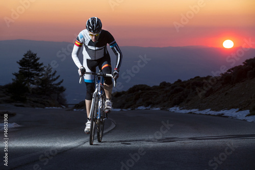 Cyclist man riding mountain bike at sunset on a mountain road