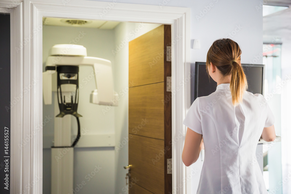 The doctor or assistant of stomatology clinic stands and looks at opened cabinet with orthopantomograph The doctor or assistant of stomatology clinic stands and looks at opened cabinet with orthopantomograph
