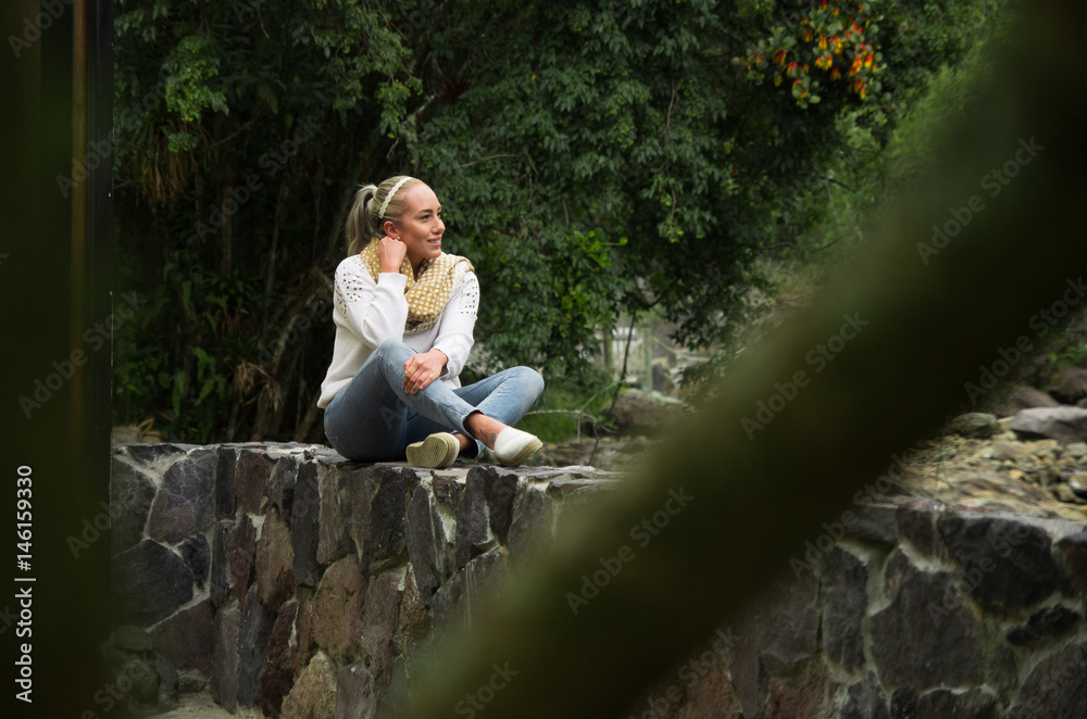 Fototapeta premium Attractive young woman sitting in a cold forest enjoying the view