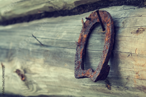 An old rusty horseshoe on an ancient wooden board. Retro. A symbol of happiness and good luck. Wooden background. Empty place for an inscription.