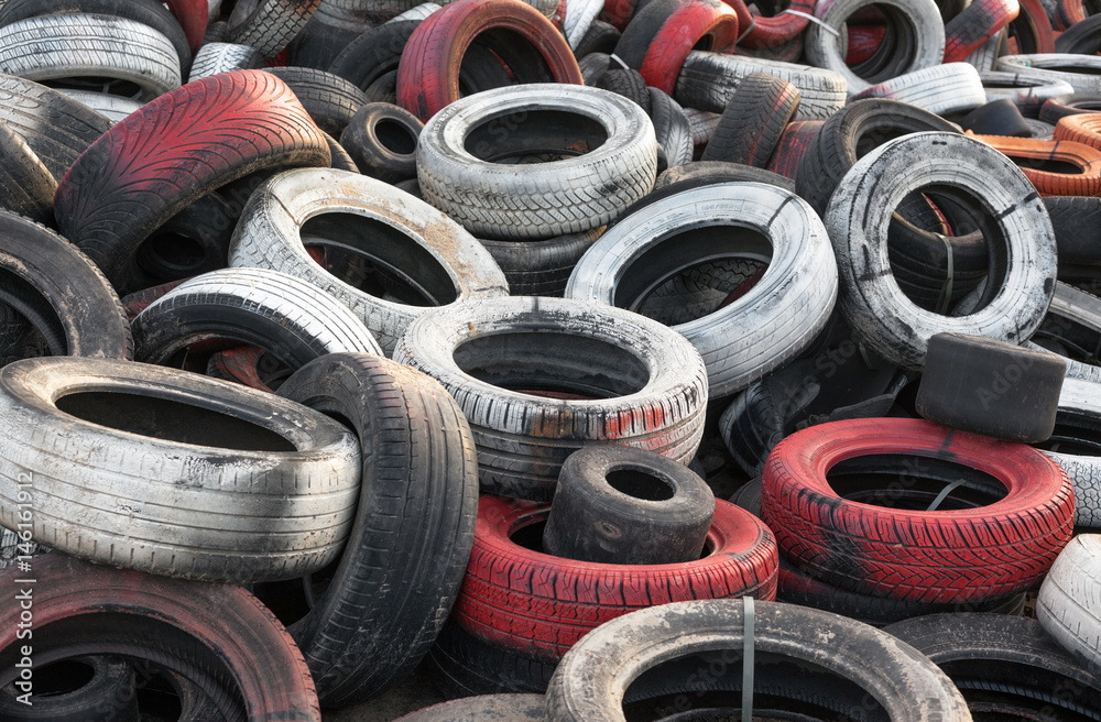 Variety of red white and black waste car tires piled in a big pile Variety of red white and black waste car tires piled in a big pile