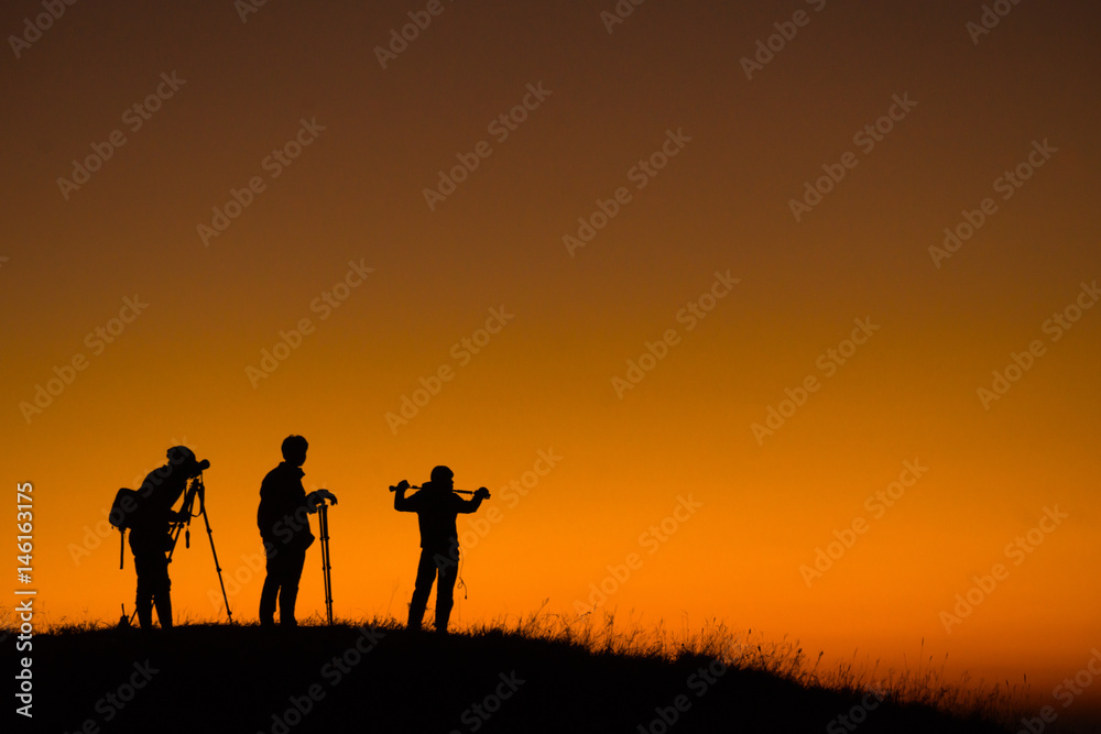 Silhouette of aphotographers top of mountain on sunset.