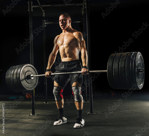 Man lifting heavy barbell in gymnasium