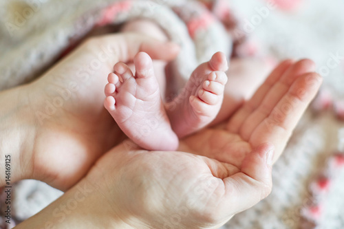 Mother holding newborn baby's feet in her hands