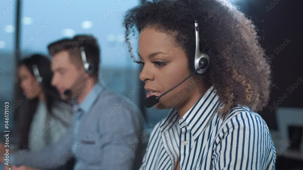 Woman talking to the client with headset and smiling while looking at camera.