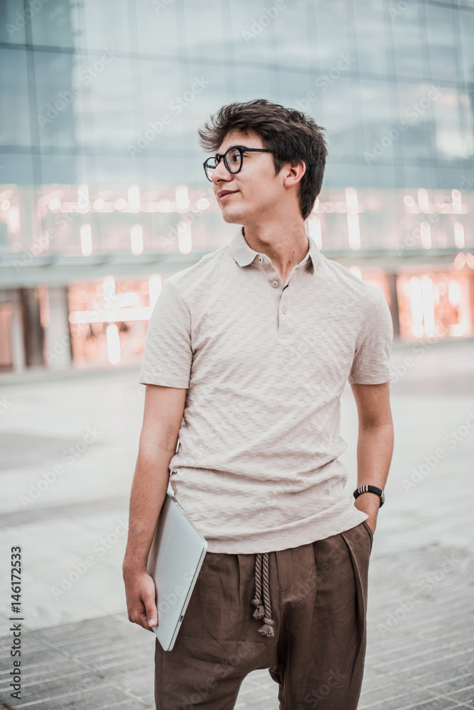 Young boy with laptop on the street. Asian man on the street with a laptop. Wearing vintage clothes