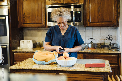 Black woman texting on cell phone in domestic kitchen