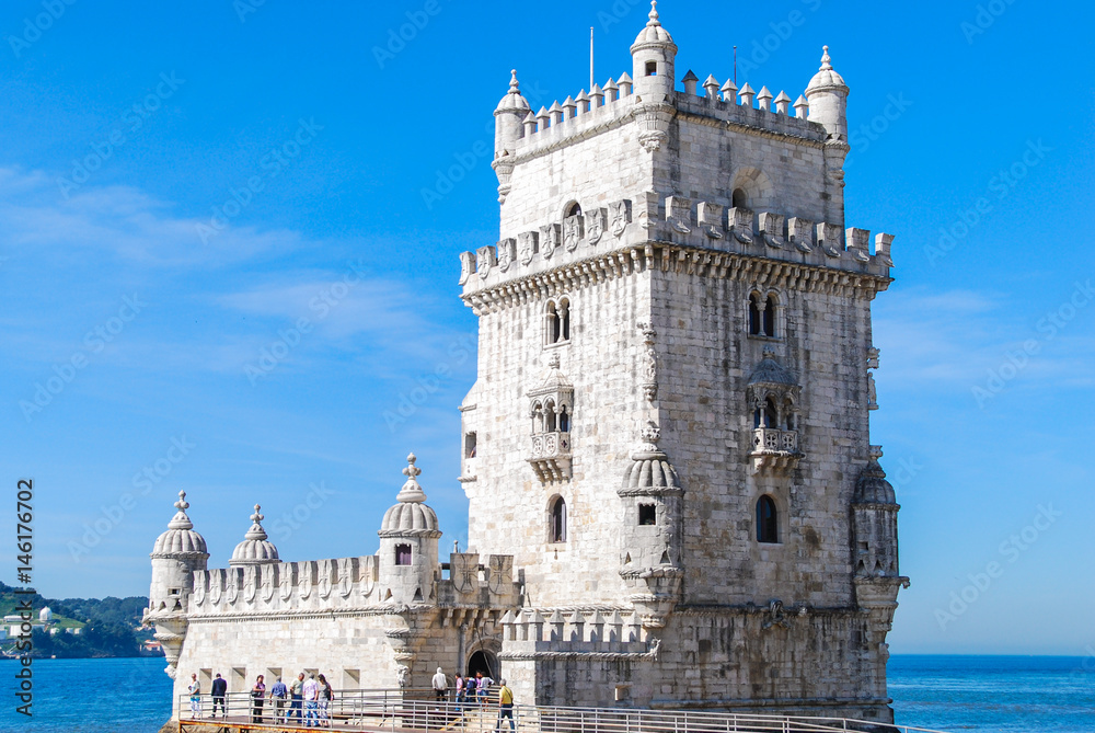 Belem tower in Lisbon, Portugal isolated with tourists in front and Atlantic ocean in the background