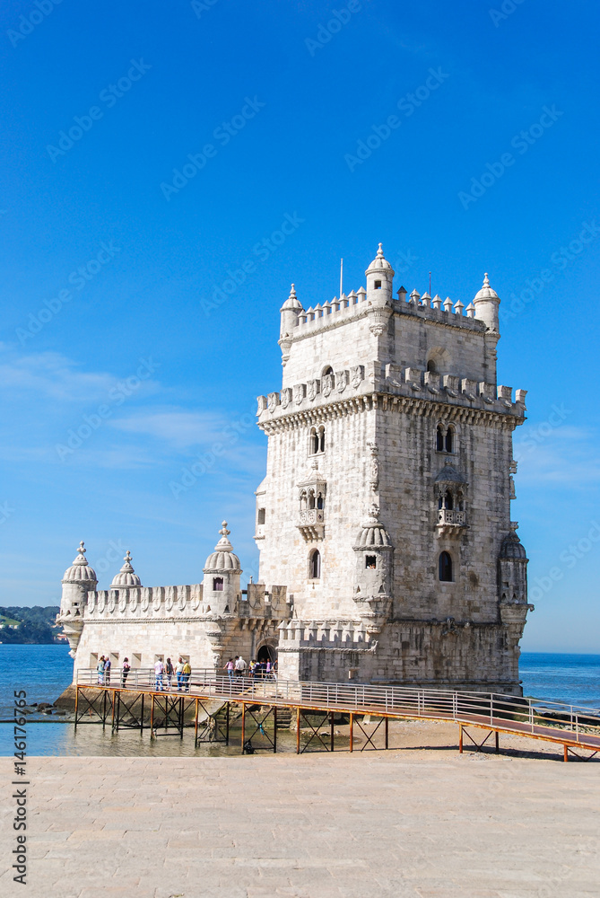 Belem tower in Lisbon, Portugal isolated with tourists in front and Atlantic ocean in the background