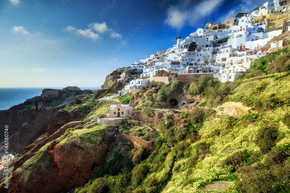 Naklejka premium Classical view from sunset point at Oia village white and blue architecture, Santorini island, Greece. Incredible evening scenery.