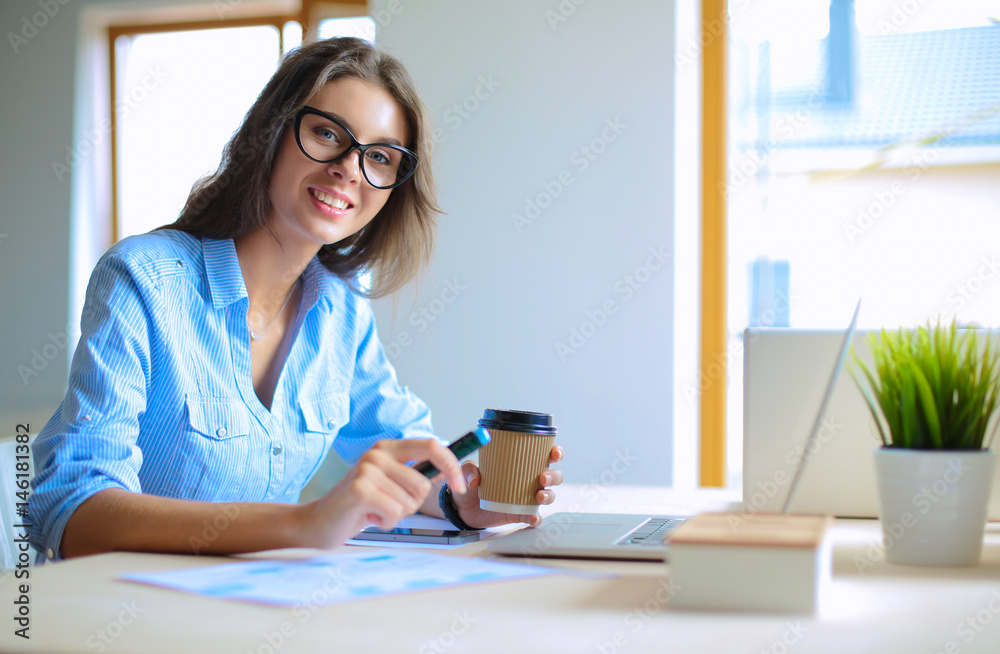 Young woman sitting in office table, looking at laptop computer screen Young woman sitting in office table, looking at laptop computer screen