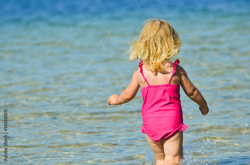 Happy little blonde girl running in the water. Happy holidays concept. Happy little blonde girl running in the water. Happy holidays concept.