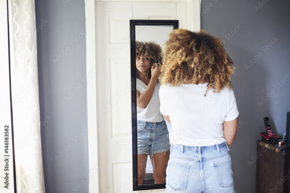 Black woman examining hair in mirror Black woman examining hair in mirror