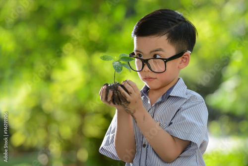 Child holding young plant in hands with a hope of good environment