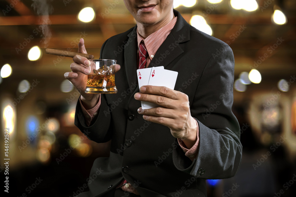 Handsome man holding glass of whiskey with cigarette and show winning in poker games. Handsome man holding glass of whiskey with cigarette and show winning in poker games.