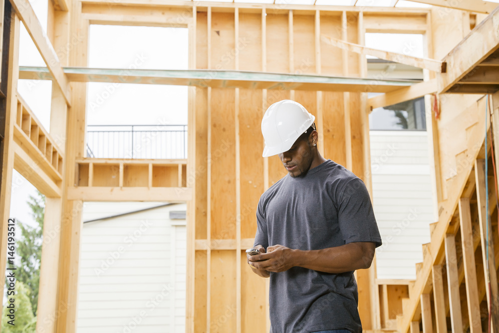 Black construction worker texting on cell phone Black construction worker texting on cell phone