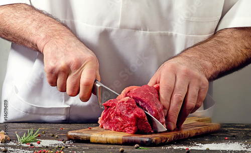 Chef cutting raw beef meat
