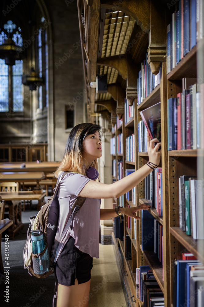 Chinese woman standing in library choosing book Chinese woman standing in library choosing book