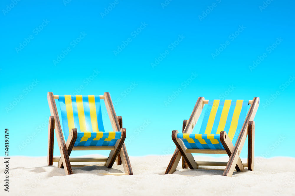 Two sunbeds at the beach on background of blue sky