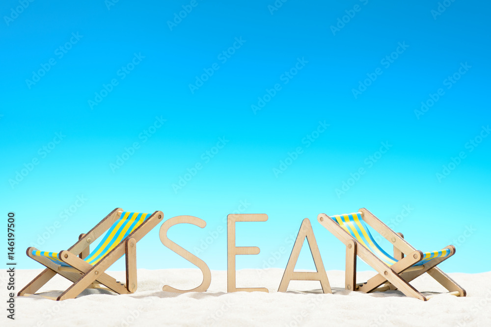 The word SEA and two sunbeds at the beach on background of blue sky The word SEA and two sunbeds at the beach on background of blue sky