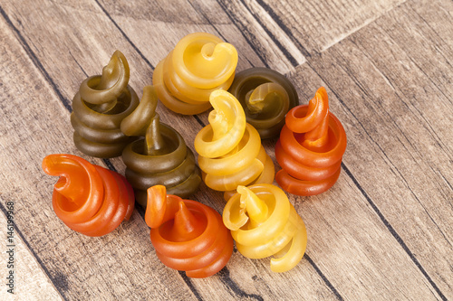 Spiral pasta trottole tricolore on wooden plank,  close up. photo