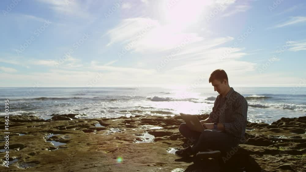 Happy attractive young man on a beach is buying something over the Internet Happy attractive young man on a beach is buying something over the Internet