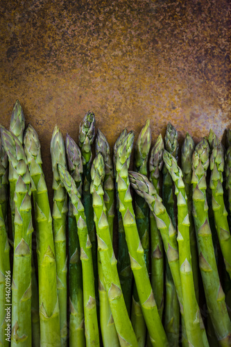 Fresh and raw green asparagus on a vintage background with space for text.