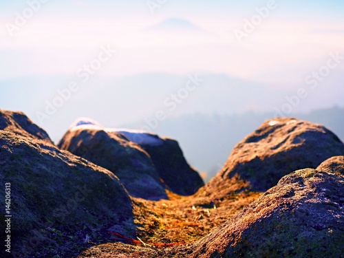 Rocky peak above inverse mist. Winter cold weather in mountains  colorful fog. Misty valley