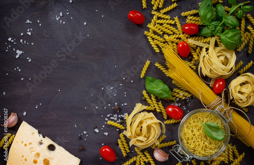 Ingredients for cooking Italian pasta - spaghetti, fusilli, fettuccine, basil, cherry tomato, garlic, pepper and cheese. Top view with space for text. photo