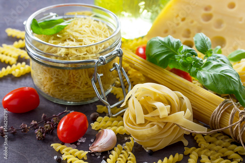 Ingredients for cooking Italian pasta - spaghetti, fusilli, fettuccine, basil, cherry tomato, garlic, pepper and cheese. photo