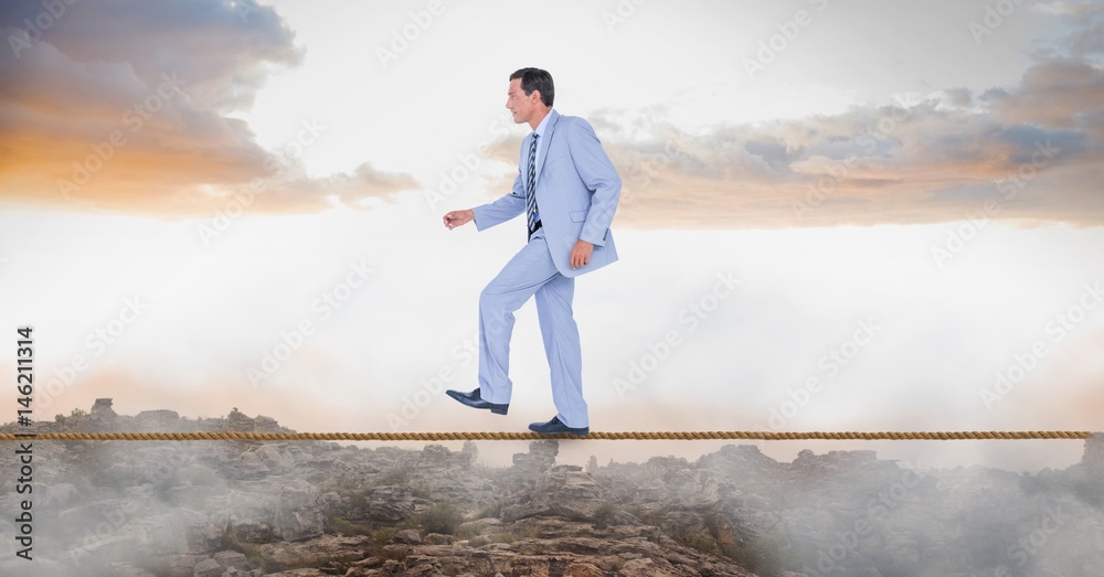 Businessman walking on rope over landscape Businessman walking on rope over landscape