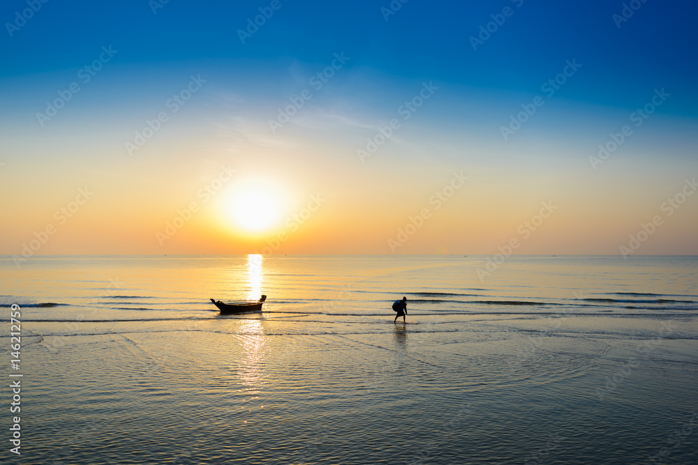 Silhouette of fishing boat and Beautiful tropical sunrise on the beach.