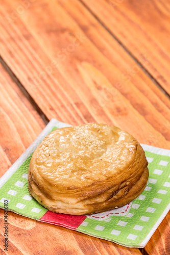 Round puff pastry with sesame on the napkin over wooden background