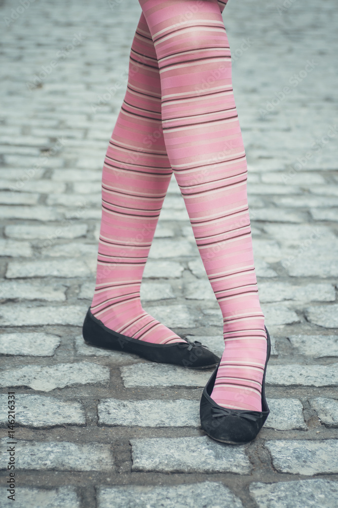 Female legs with pink trendy stripped tights and black ballerina flat shoes  over a cobbled street, posing in a funny ballet step Stock Photo | Adobe  Stock