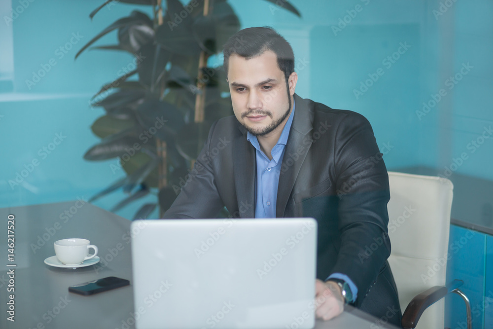 Young financial businessman with laptop sitting at desk Young financial businessman with laptop sitting at desk