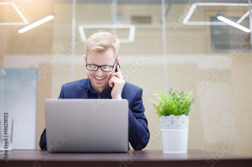 Portrait of cheerful young businessman working in office.