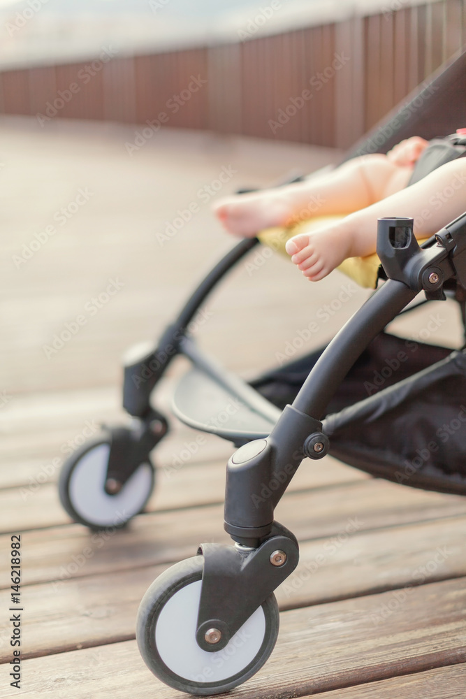 Obraz premium Baby sleeping in stroller outdoors. Cute baby barefeet in pushchair