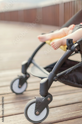 Baby sleeping in stroller outdoors. Cute baby barefeet in pushchair