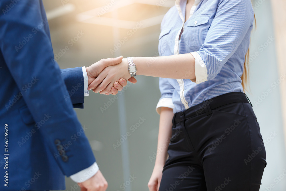 Close-up of two business people shaking hands in modern bright office