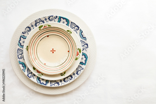 Stack of empty ceramic plates isolated on white background with copy space. Cheerful colorful dishes decorated with floral pattern. Beautiful vintage crockery top view