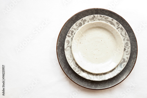 Stack of empty ceramic plates isolated on white background with copy space. Stylish gray dishes decorated with floral pattern. Beautiful vintage crockery top view