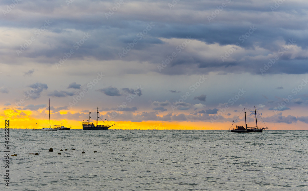 Seascape at sunset time with masted ships