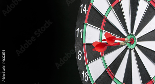 Dartboard on a black background with arrows hitting the center target