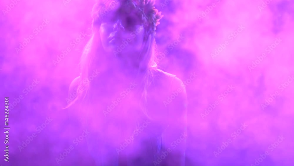 Closeup face of pretty woman in flower wreath dancing at the party over disco lights background